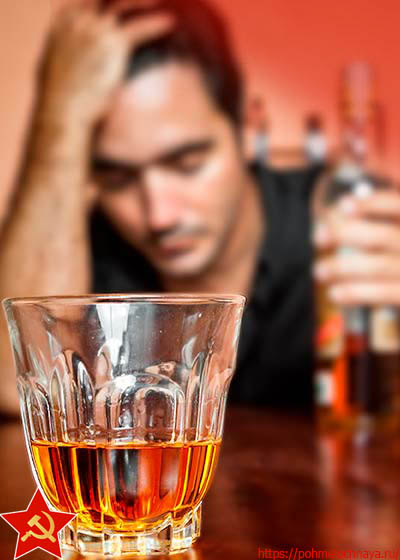 стакан с алкоголем крупным планом на фоне грустного мужчины